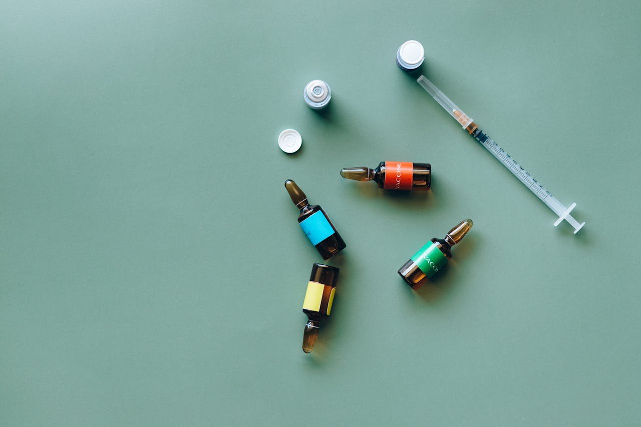about-02 Flat lay of medical ampoules and syringe on a green background, ideal for healthcare themes.